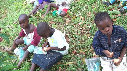 orphan children eating on the grass